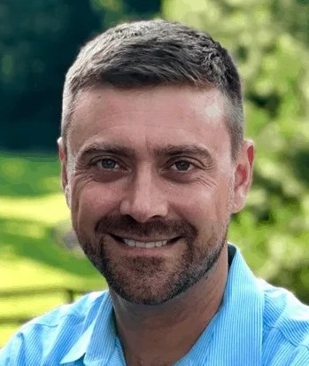 Nick Snider, smiling, outdoors in a light blue shirt